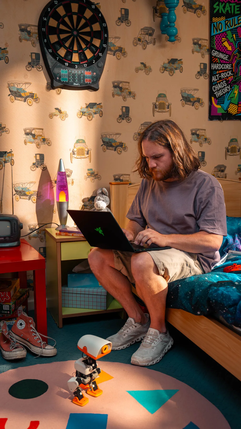 A Microduck standing on a bedroom rug while its owner codes on the bed behind it